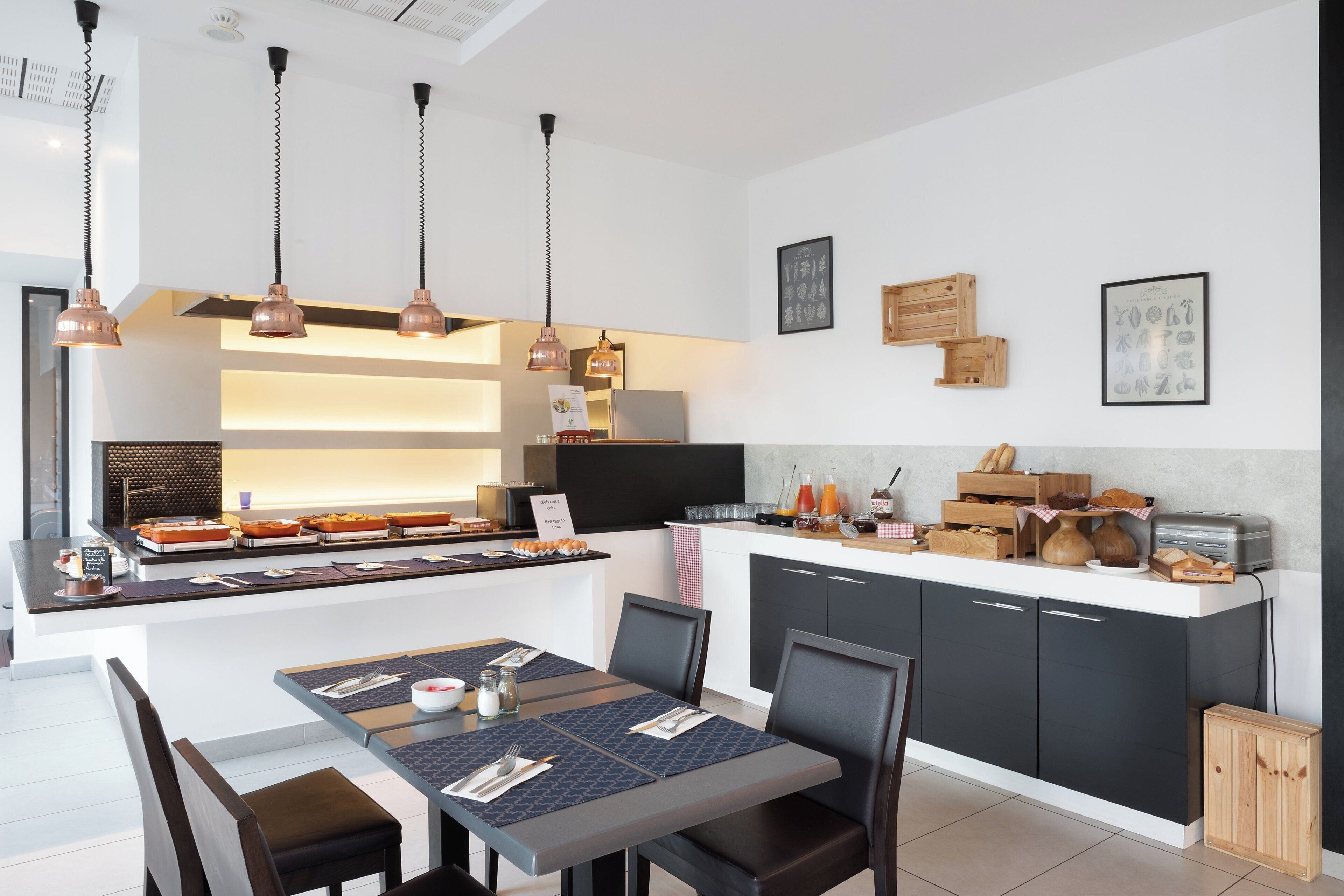 Een moderne keuken met een ontbijtbalk, hanglampen en een eethoek met een tafel voor twee personen.