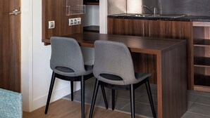 A compact kitchen with a wooden countertop, two grey chairs, and a built-in microwave. - Holiday Inn Marseille Airport by IHG (Vitrolles)