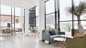 A modern interior with large windows, a grey sofa, a green armchair, and a small table.