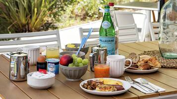 Una mesa de desayuno con diversos alimentos, incluyendo frutas, pan y una botella de agua Pellegrino.