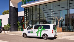 A white van with green branding parked in front of a Holiday Inn hotel. - Holiday Inn Marseille Airport by IHG (Vitrolles)