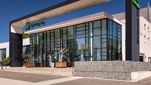 A modern Holiday Inn hotel with a glass facade, outdoor seating area, and a prominent entrance. - Holiday Inn Marseille Airport by IHG (Vitrolles)