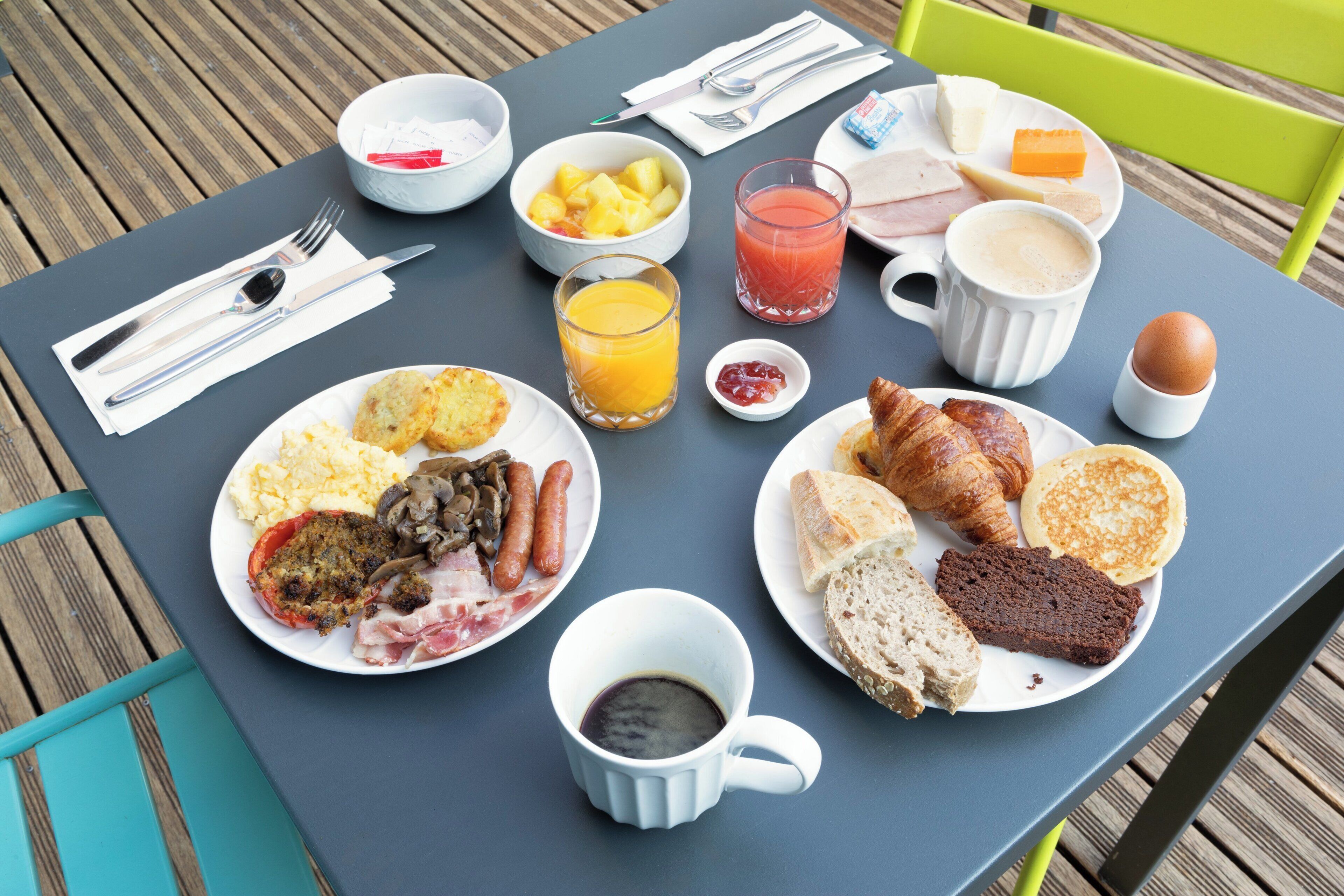 A table set with breakfast items including eggs, sausages, toast, and a croissant.