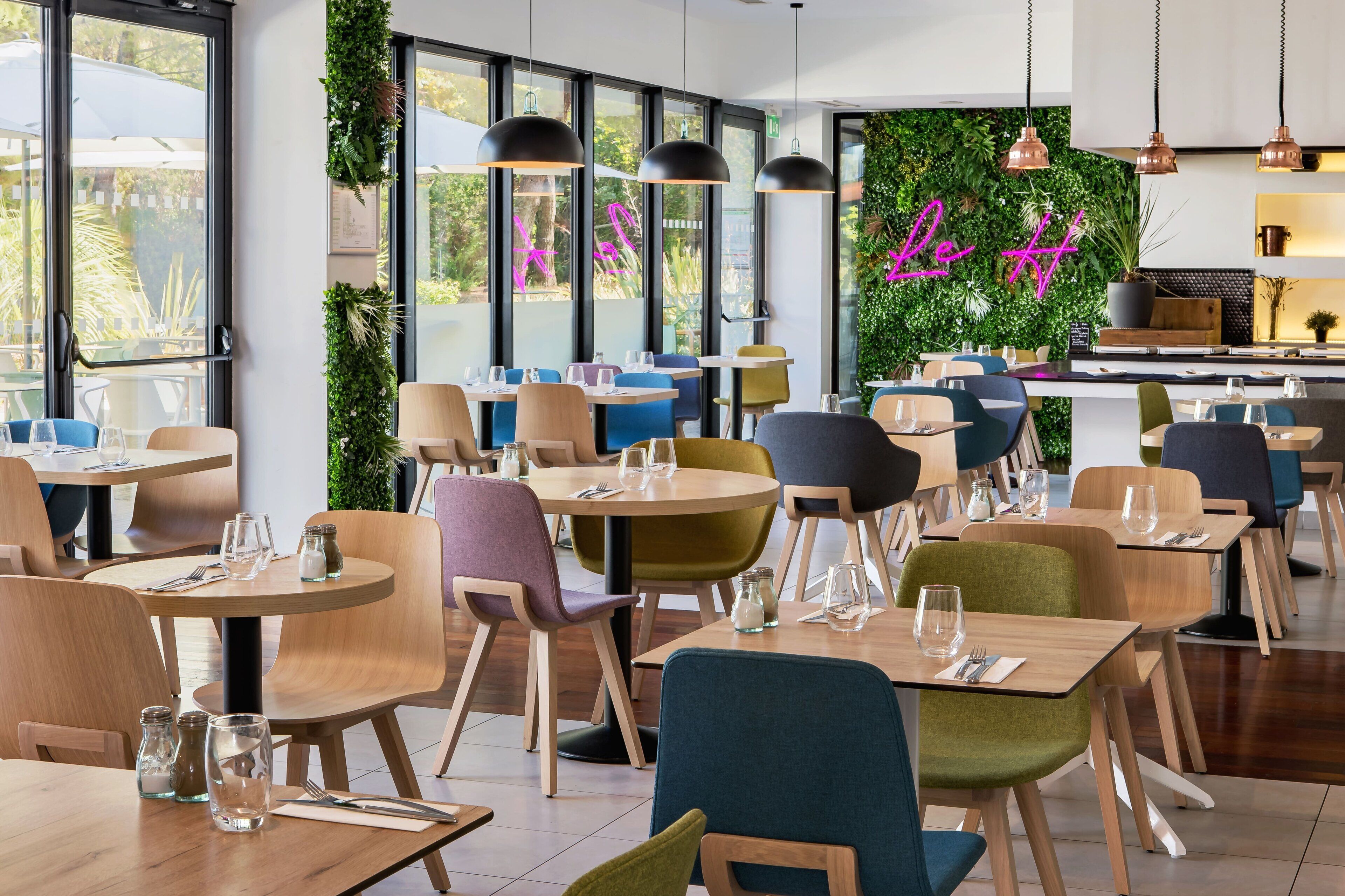 Interior de restaurante con mesas redondas, sillas y lámparas colgantes.