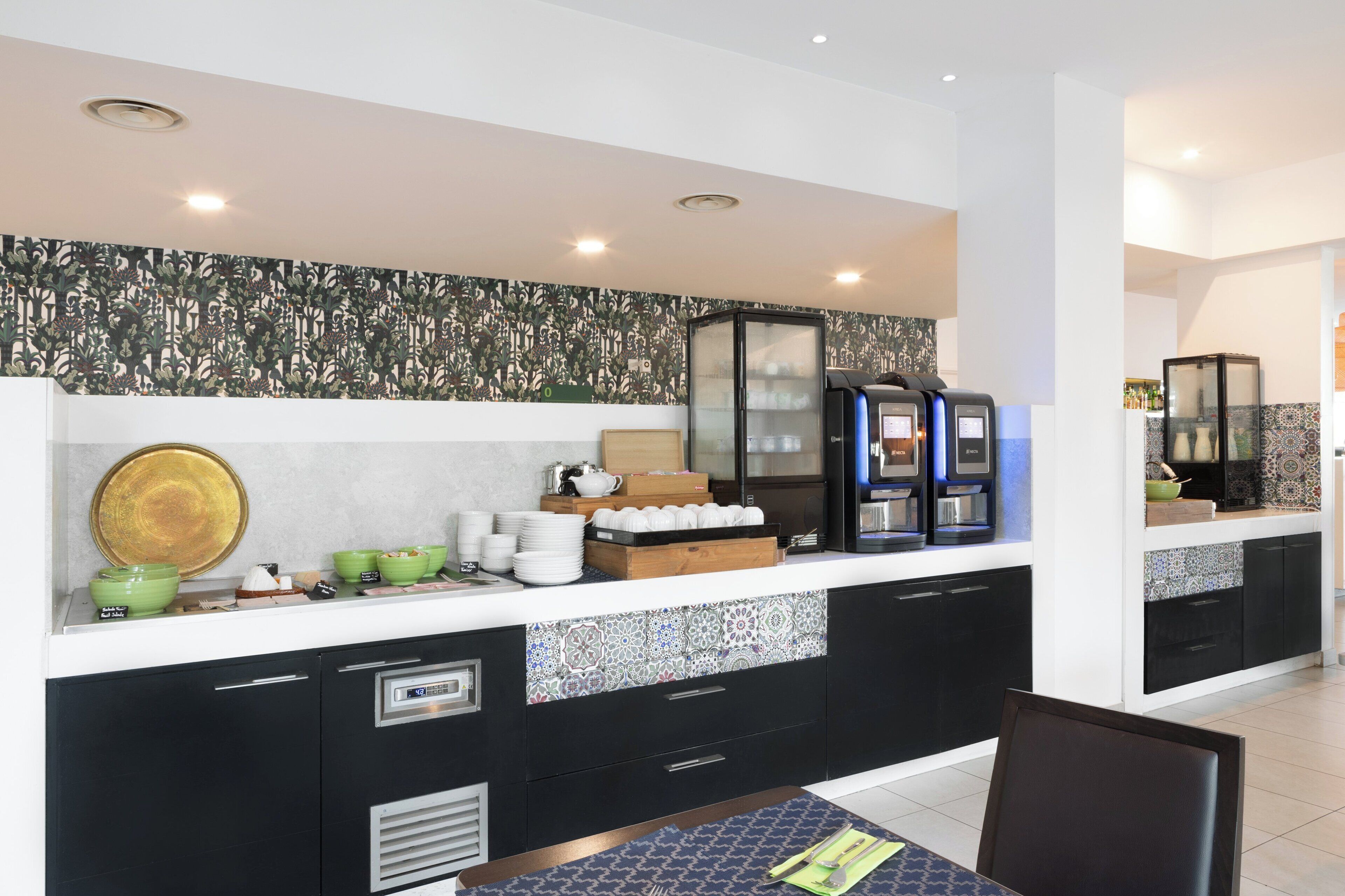 Una cucina moderna con mobili neri, una schiena a parete decorata e una macchina per il caffè.