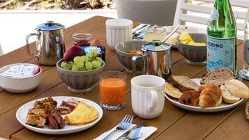 Une table de petit-déjeuner avec une variété d’aliments, notamment des œufs, des toasts et des viennoiseries, ainsi qu’une bouteille d’eau et une cafetière.