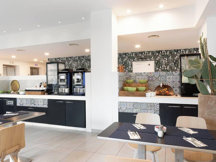 A modern kitchen with a central island, a dining area with a table set for two, and a large cactus plant.