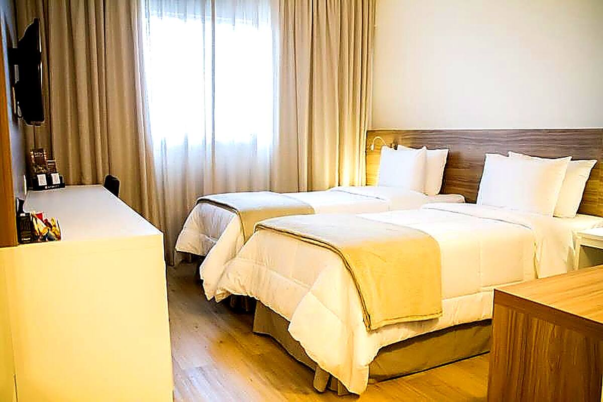 Habitación de hotel con dos camas, un escritorio y una televisión.