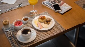 Ein Frühstückstisch mit Essen, Orangensaft, Kaffee und einer Zeitung.
