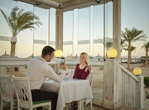 Un couple est assis à une table, profitant de la vue sur les palmiers et les parasols de plage.
