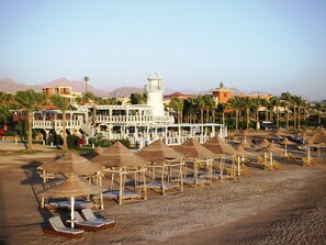 Aan een privéstrand, wit zand, ligstoelen, parasols