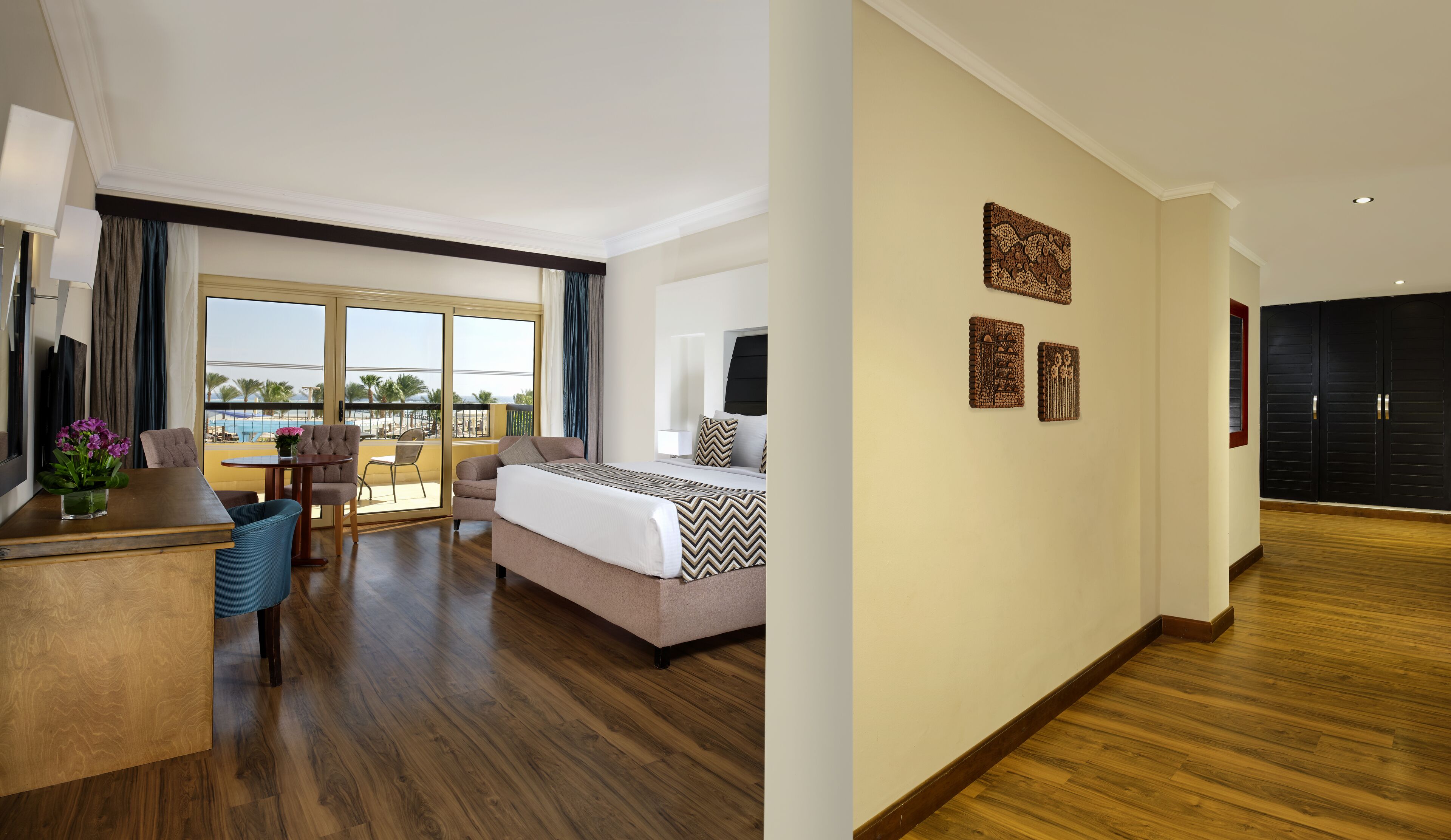 Une chambre d’hôtel avec un lit, un bureau, une chaise et une vue sur la plage.