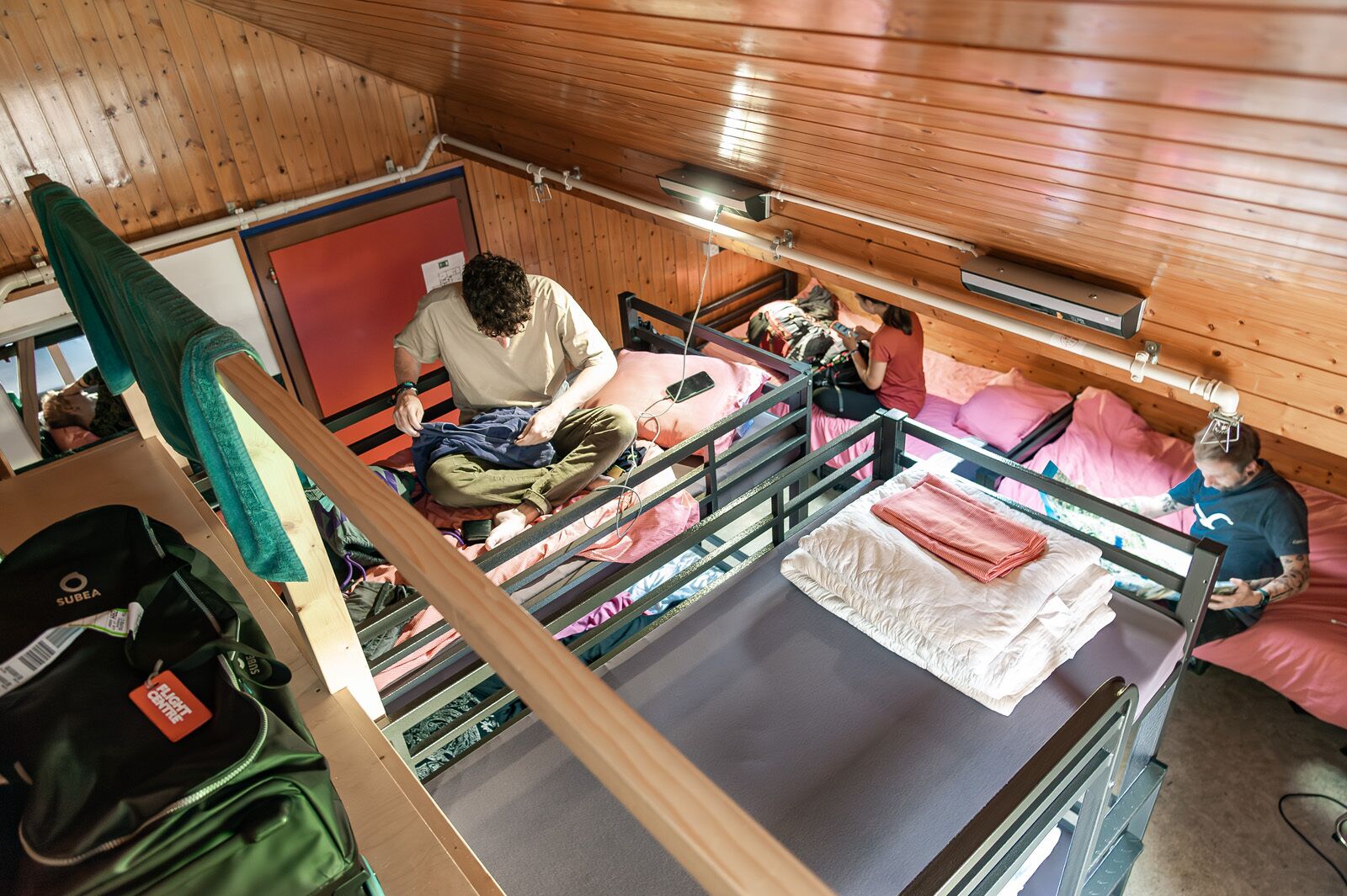 A cabin interior with bunk beds, wooden walls, and a visible window.