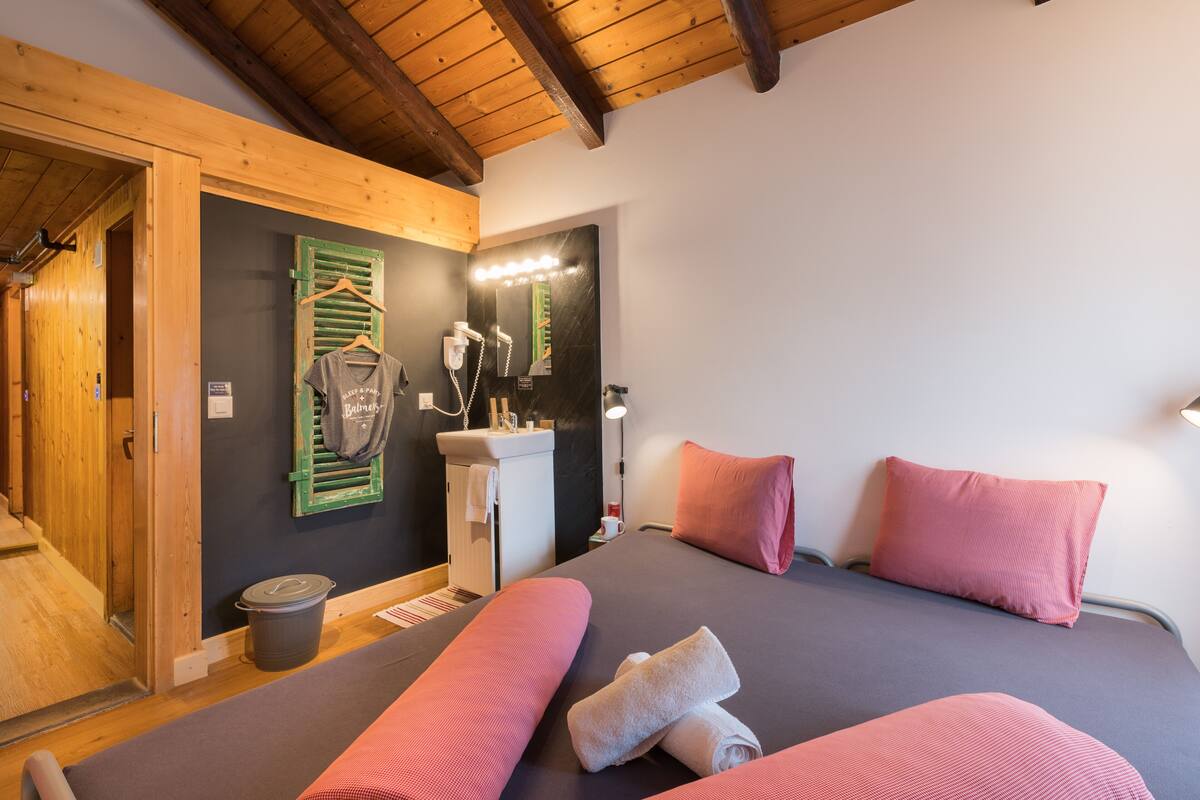 Un dormitorio con cama, almohadas, tocador con espejo y un perchero para toallas.