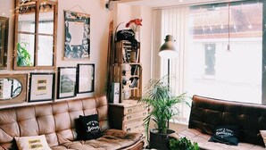 A cozy living room with a brown leather sofa, a wooden coffee table, and a bookshelf filled with books and decorative items. - Balmers Hostel (Matten bei Interlaken)