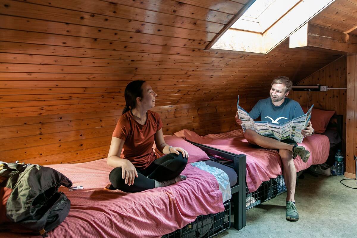Una habitación pequeña con paneles de madera, una cama litera y una mochila en el suelo.