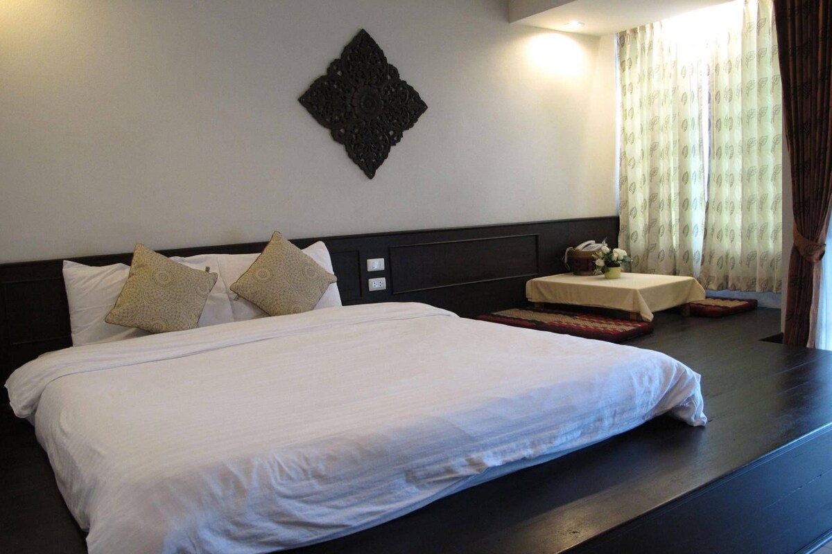 A hotel room with a large bed, a bedside table with a lamp, and a decorative wall piece.