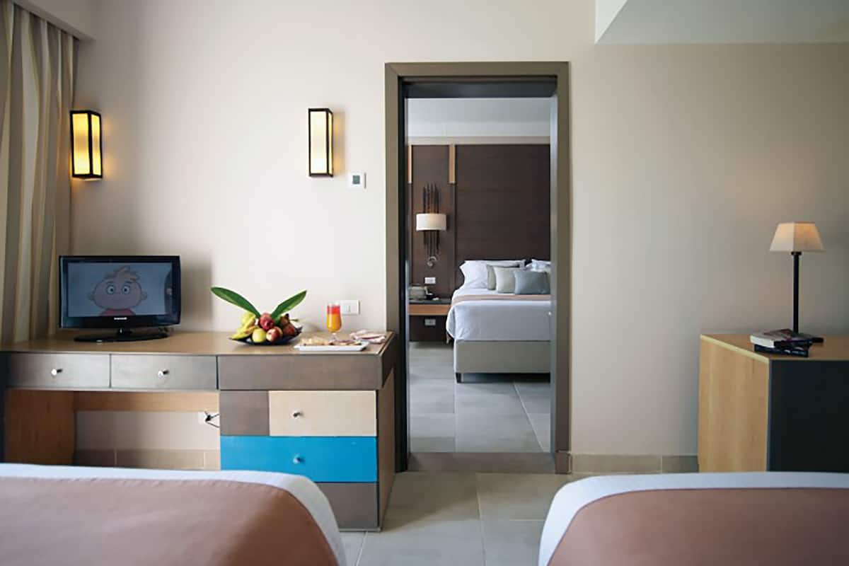 Een hotelkamer met een bed, een bureau met een computer, een lamp en een televisie.