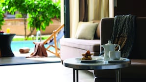 Una habitación acogedora con vistas a una piscina, un sofá, una mesa con tetera y taza, y una silla.