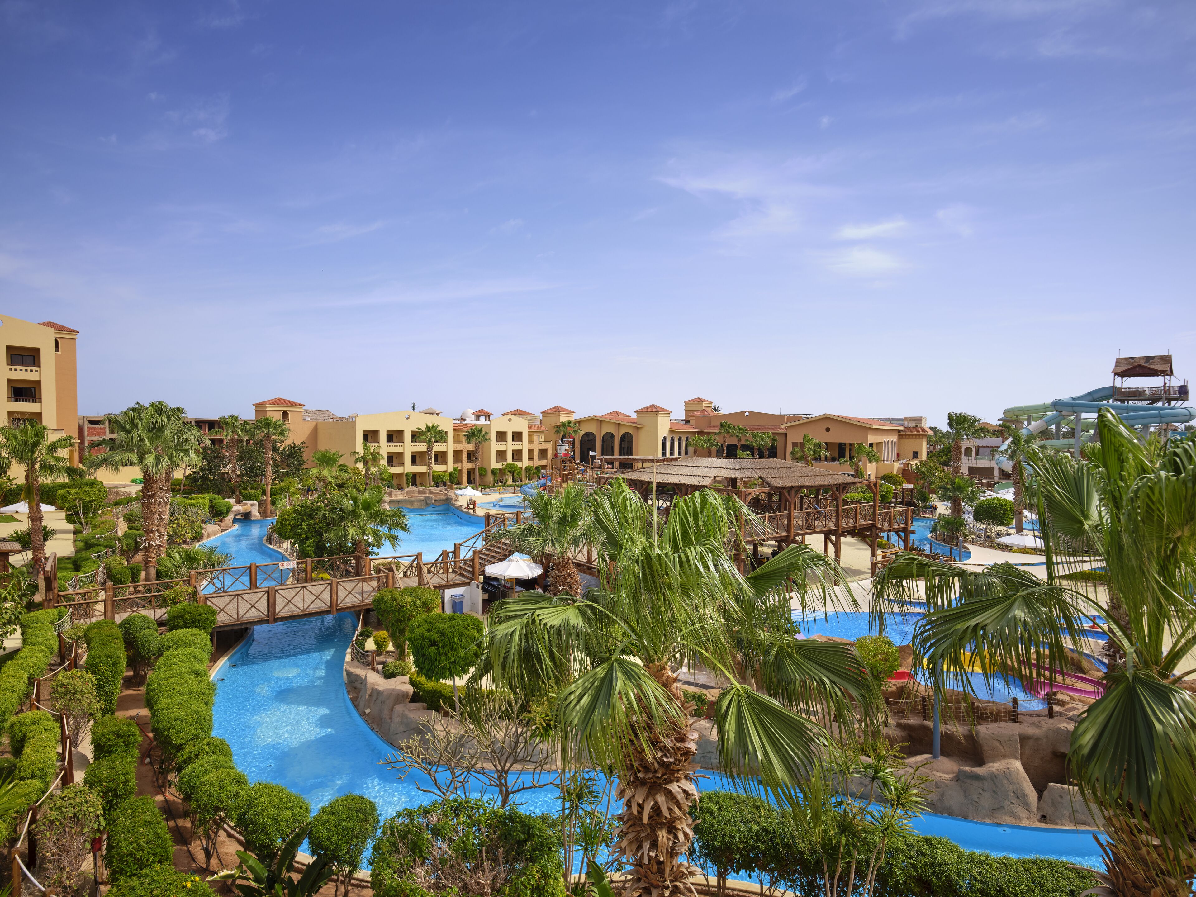 Ein Resort mit mehreren Schwimmpools, Palmen und einer Rutsche.