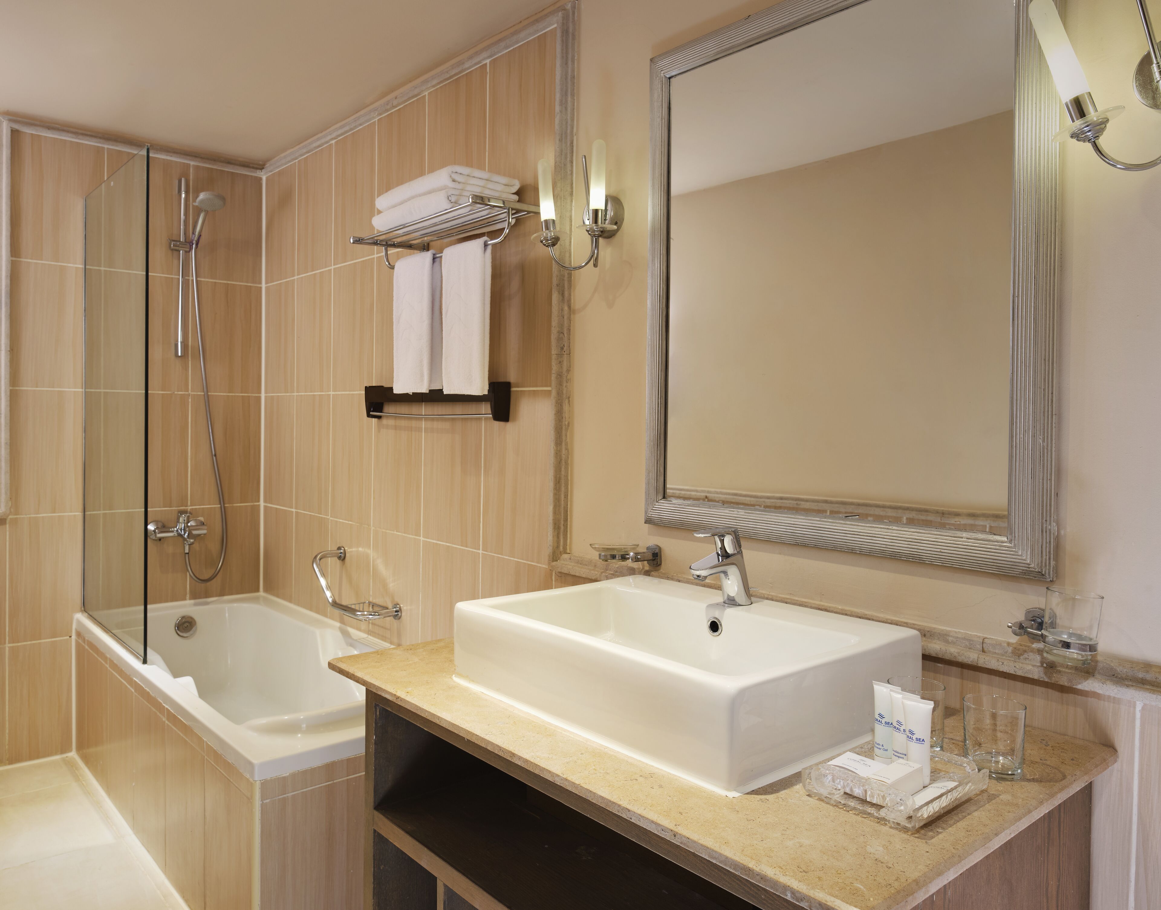 A modern bathroom with a bathtub, a large sink, a mirror, and a towel rack.