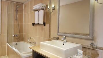 A modern bathroom with a bathtub, a large sink, a mirror, and a towel rack.