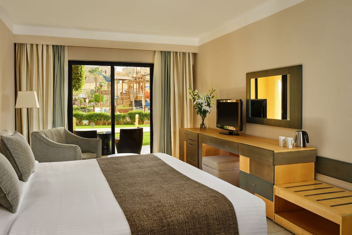 Hotelkamer met een groot bed, een bureau met een televisie, een stoel en uitzicht op buiten.