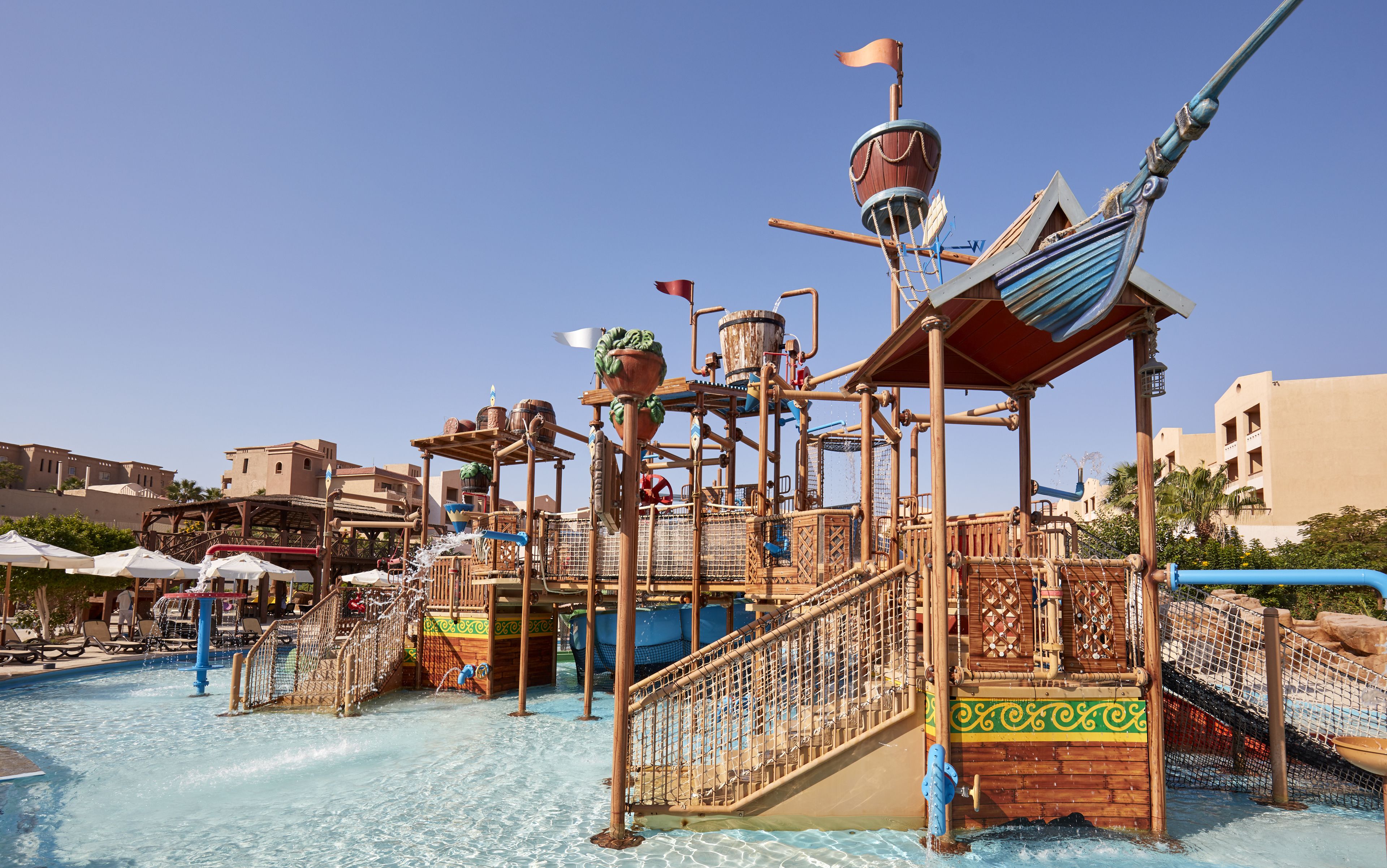 A water park with a pirate-themed play structure, including slides and climbing areas.