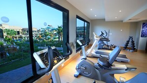 Un gimnasio moderno con equipamiento de ejercicio y amplias ventanas con vistas a una zona turística.