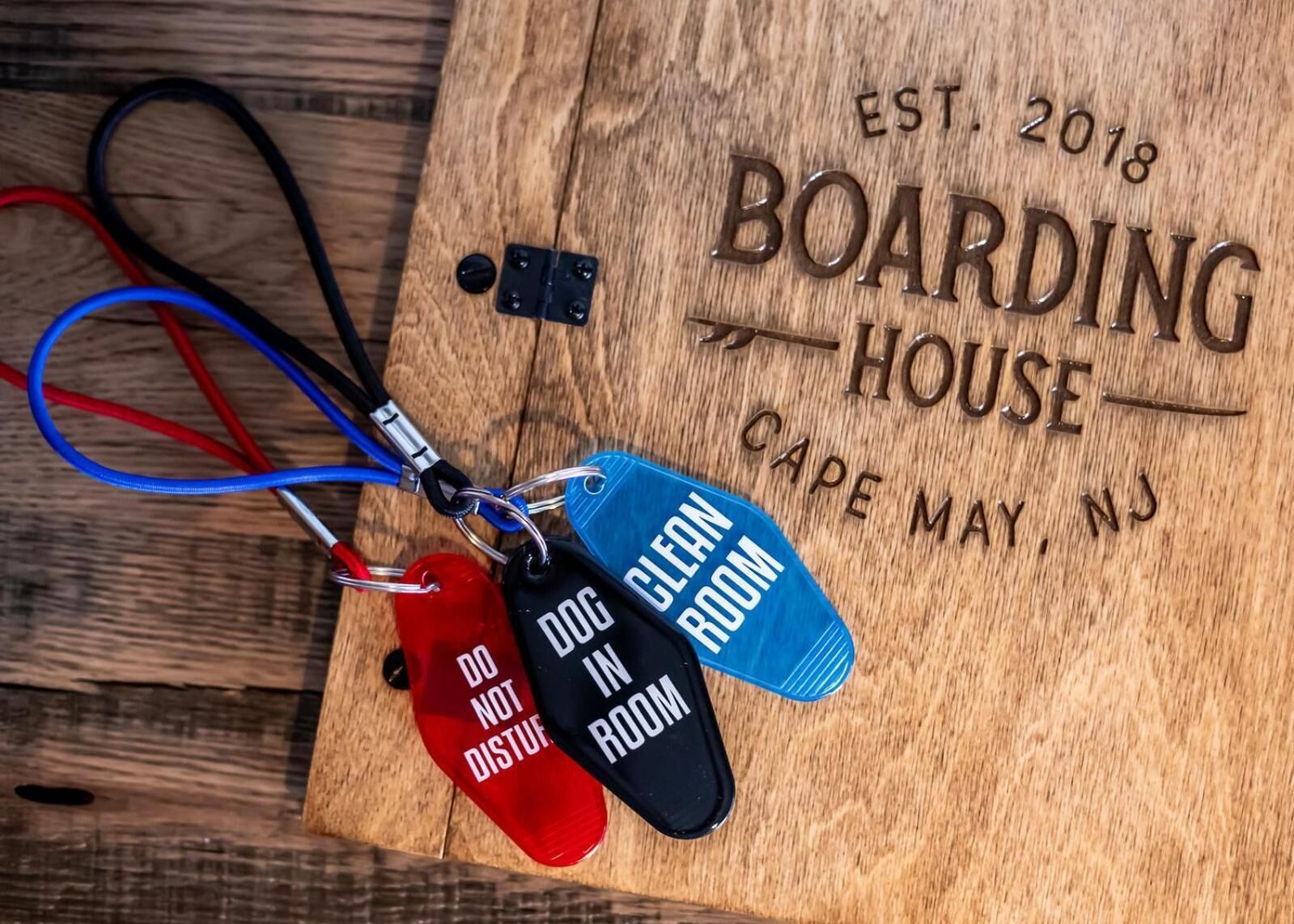 A wooden plaque with "EST. 2018 BOARDING HOUSE CAPE MAY, NJ" engraved on it.
