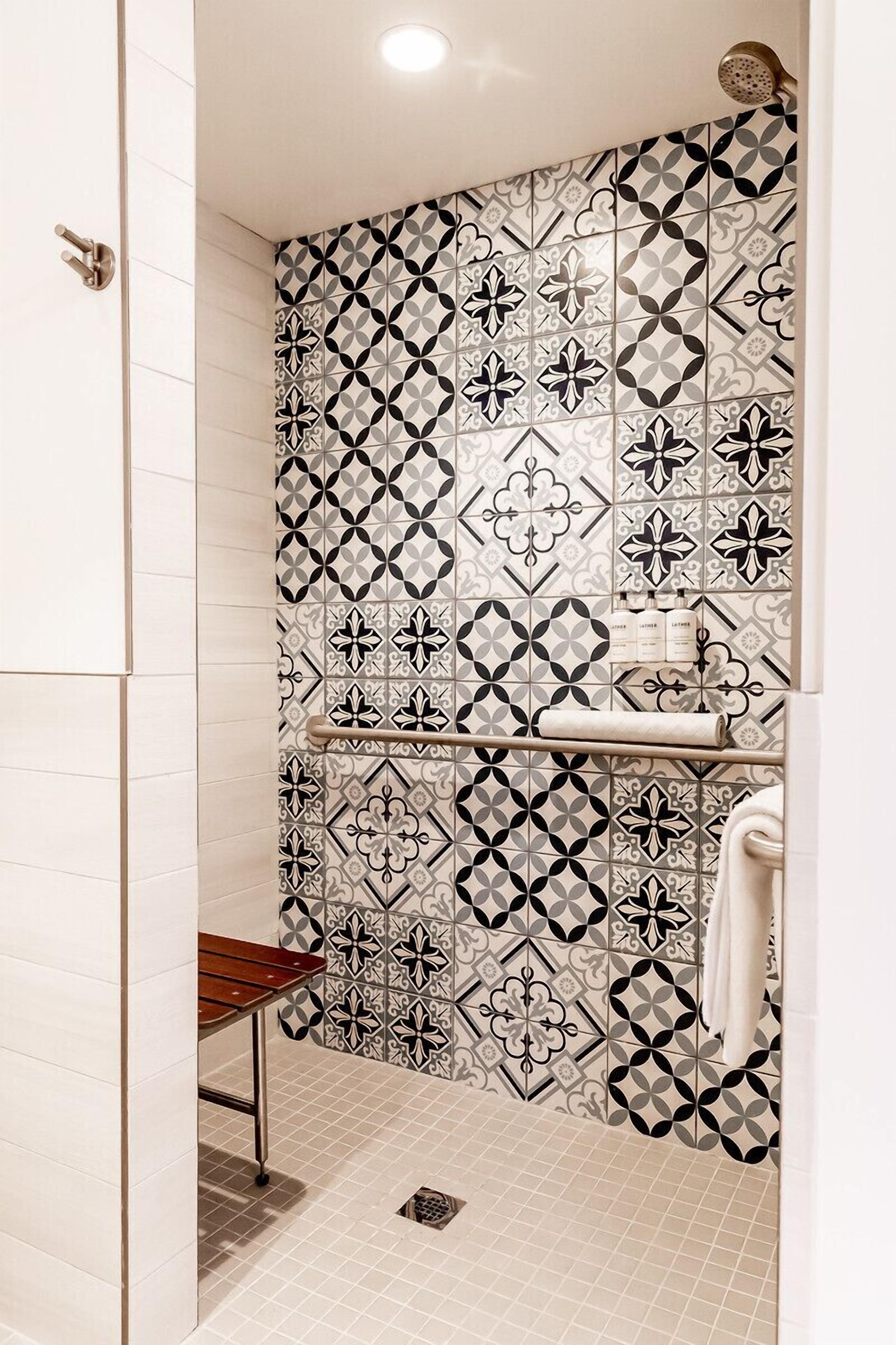 A bathroom with patterned tiles, a towel rack, and a shower.