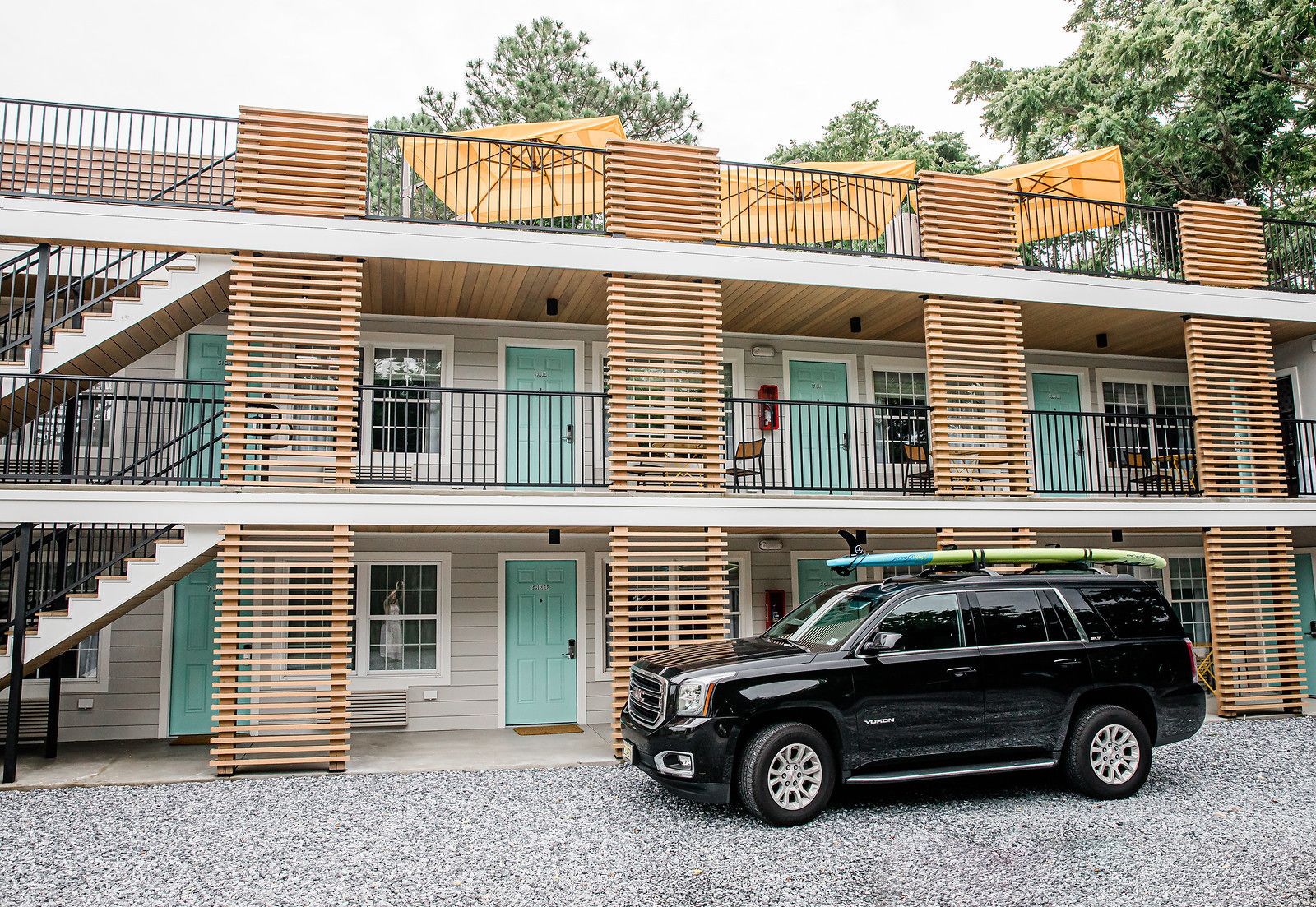 Ein mehrgeschossiges Gebäude mit einem schwarzen SUV davor.