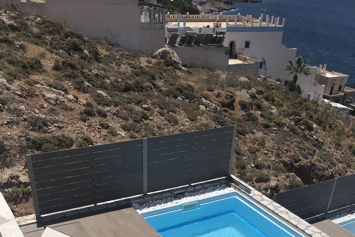 A rooftop swimming pool with lounge chairs and a view of the coastline.