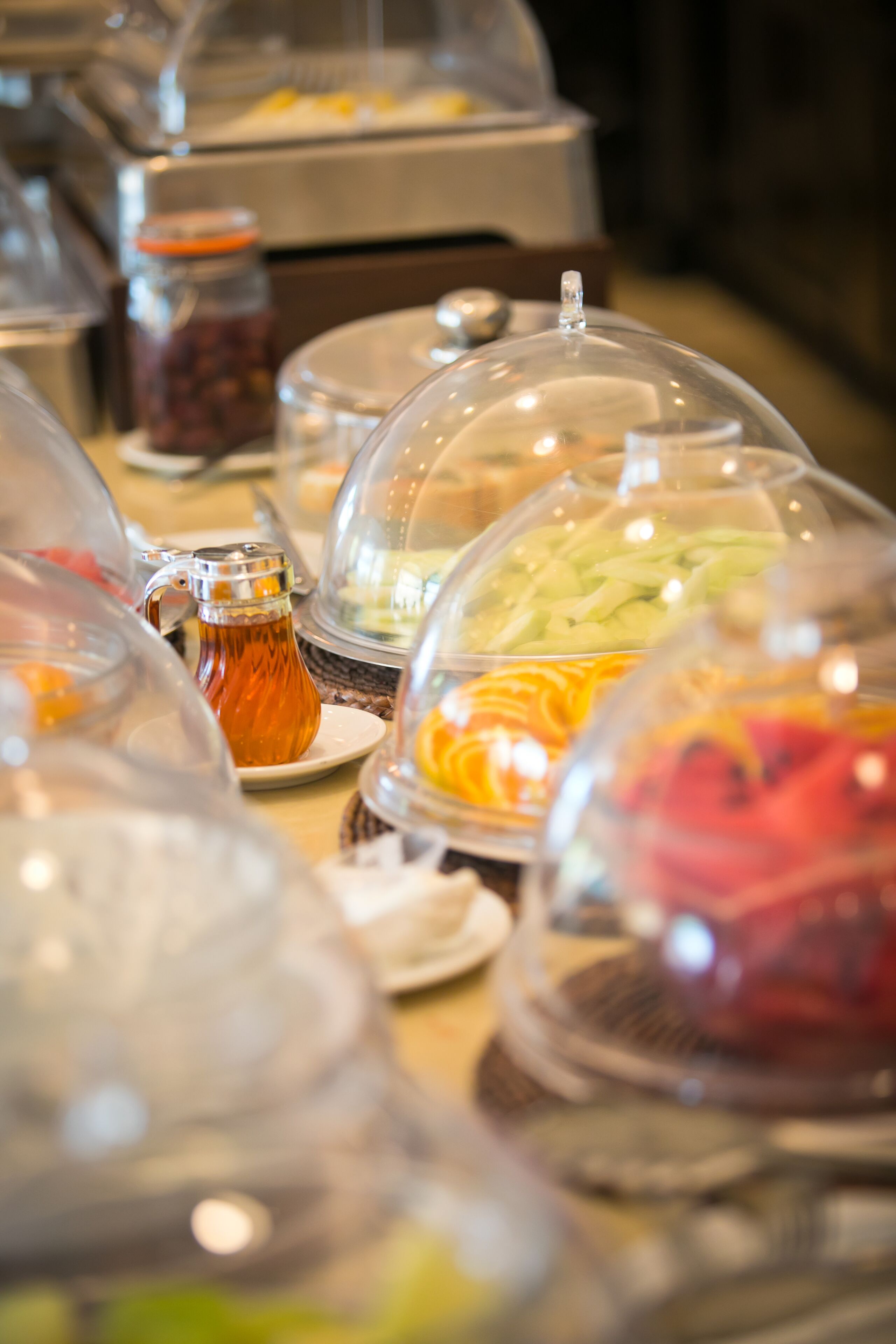 Een buffet met diverse gerechten, afgedekt met doorzichtige koepels.