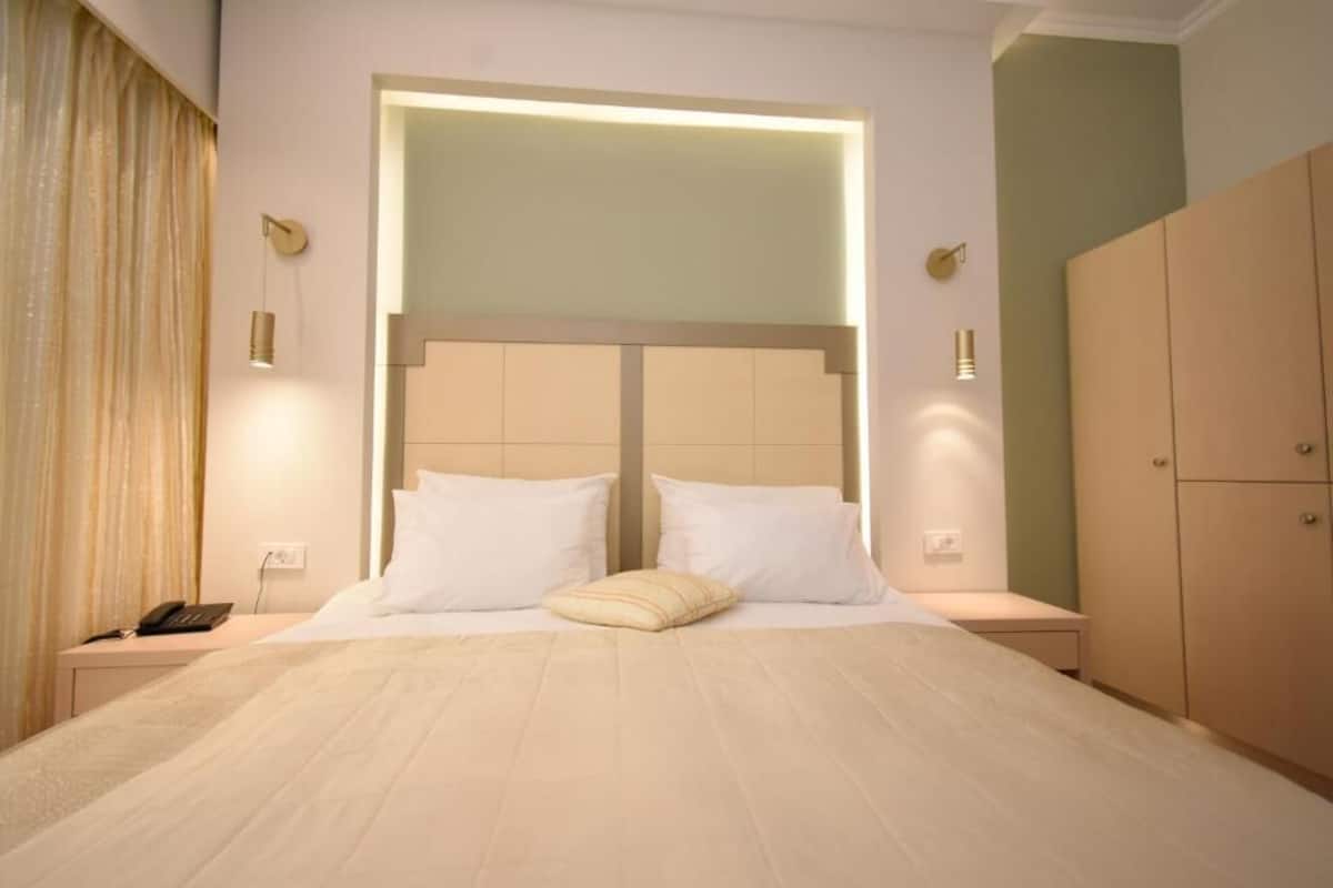 A hotel room with a large bed, bedside tables, a telephone, and a wardrobe.