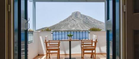 A balcony with two wooden chairs and a table, overlooking a mountain.
