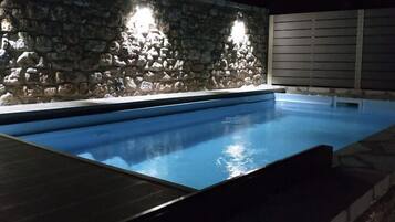 Una piscina con un muro de piedra y dos luces.