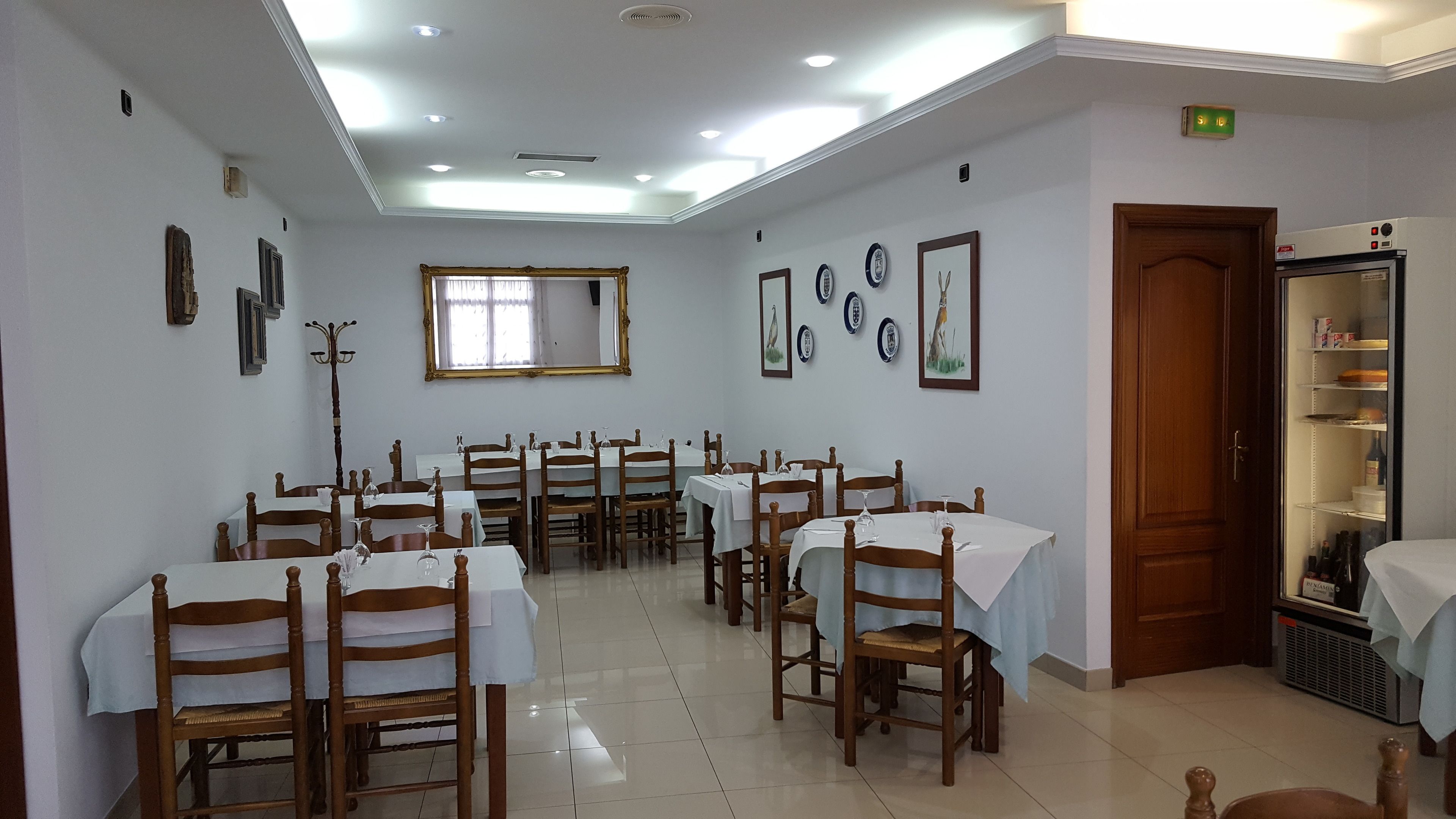 A dining area with multiple tables and chairs, a wooden door, and wall-mounted decor.