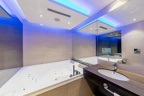 A modern bathroom with a large bathtub, a wooden vanity, and a large mirror. - Diamante Mhotel (Collegno)