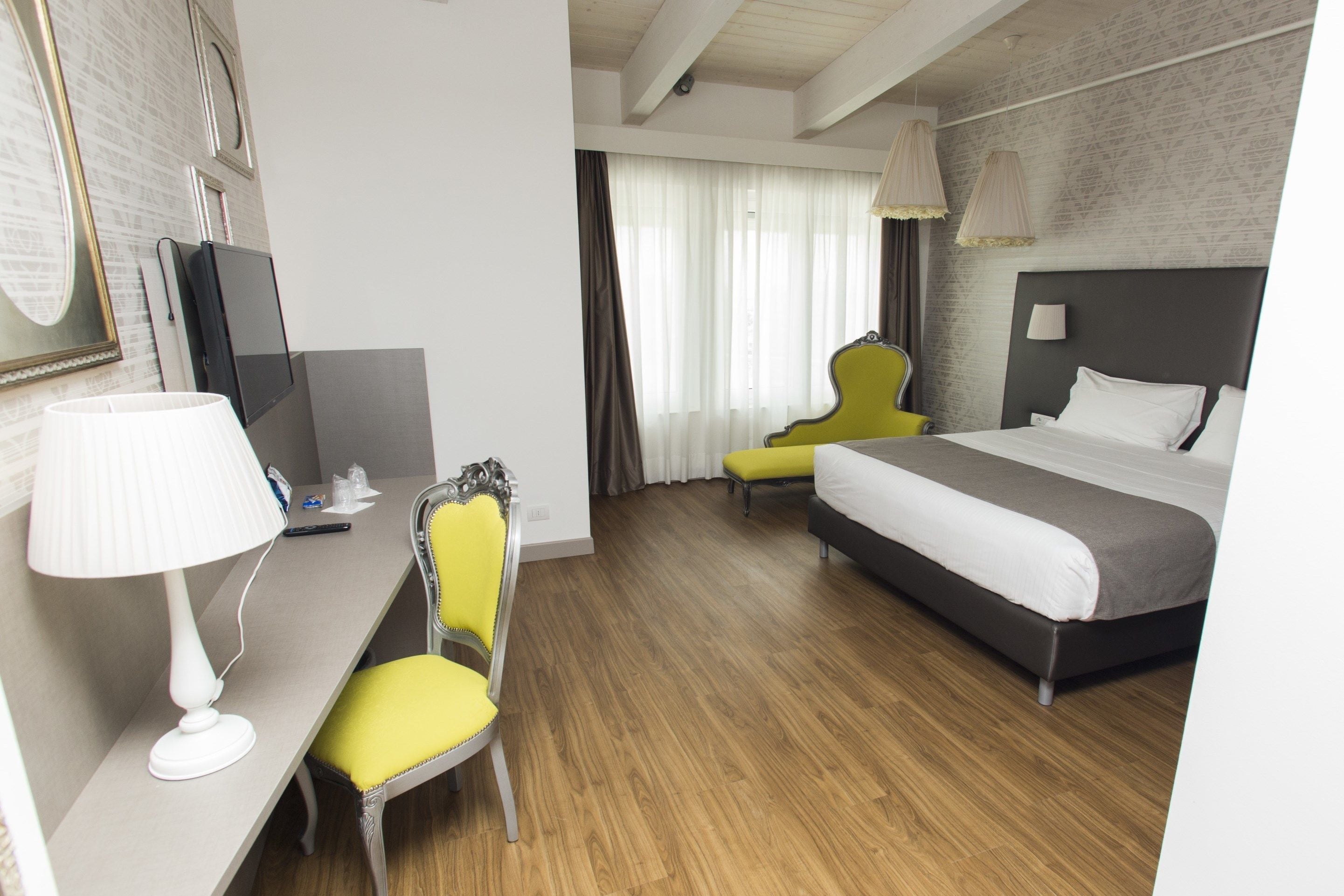 A hotel room with a bed, a desk with a lamp, a chair, and a television.