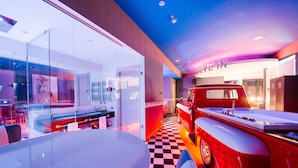 A modern interior with a checkered floor, a red vintage car, and a 'Drive In' sign. - Diamante Mhotel (Collegno)