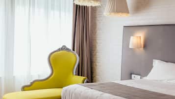 A hotel room with a bed, a yellow armchair, and a wall-mounted lamp.