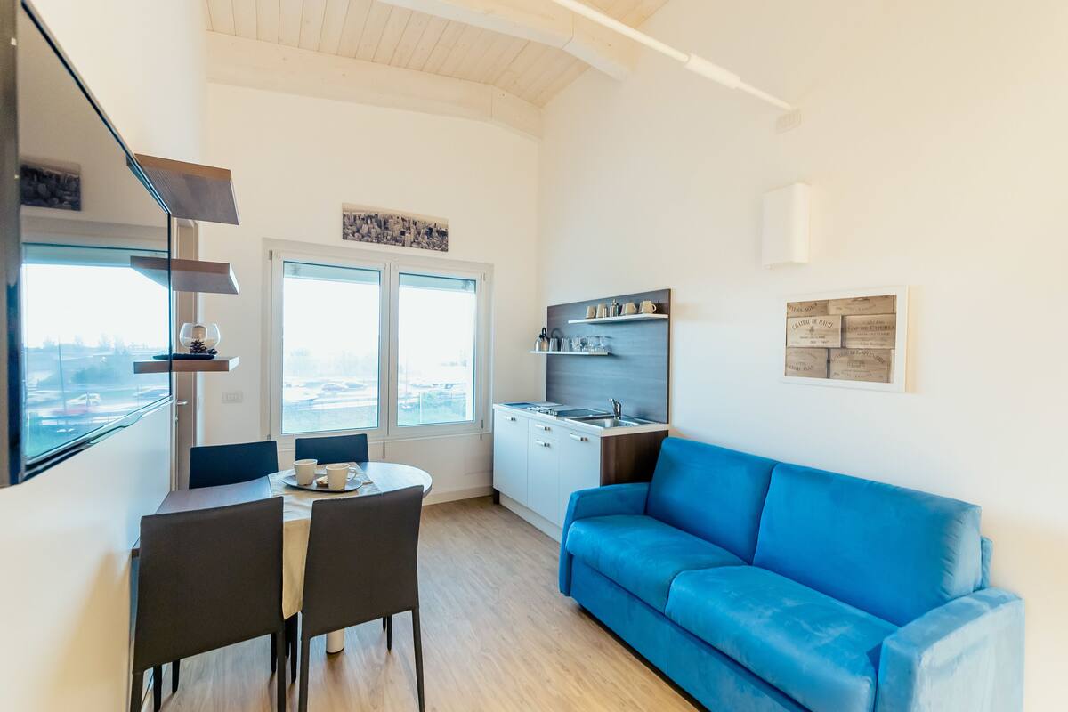 A compact living space with a dining area, kitchenette, and a blue sofa.