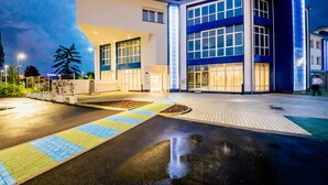A modern building with a flat roof, large windows, and a paved entrance area. - Diamante Mhotel (Collegno)