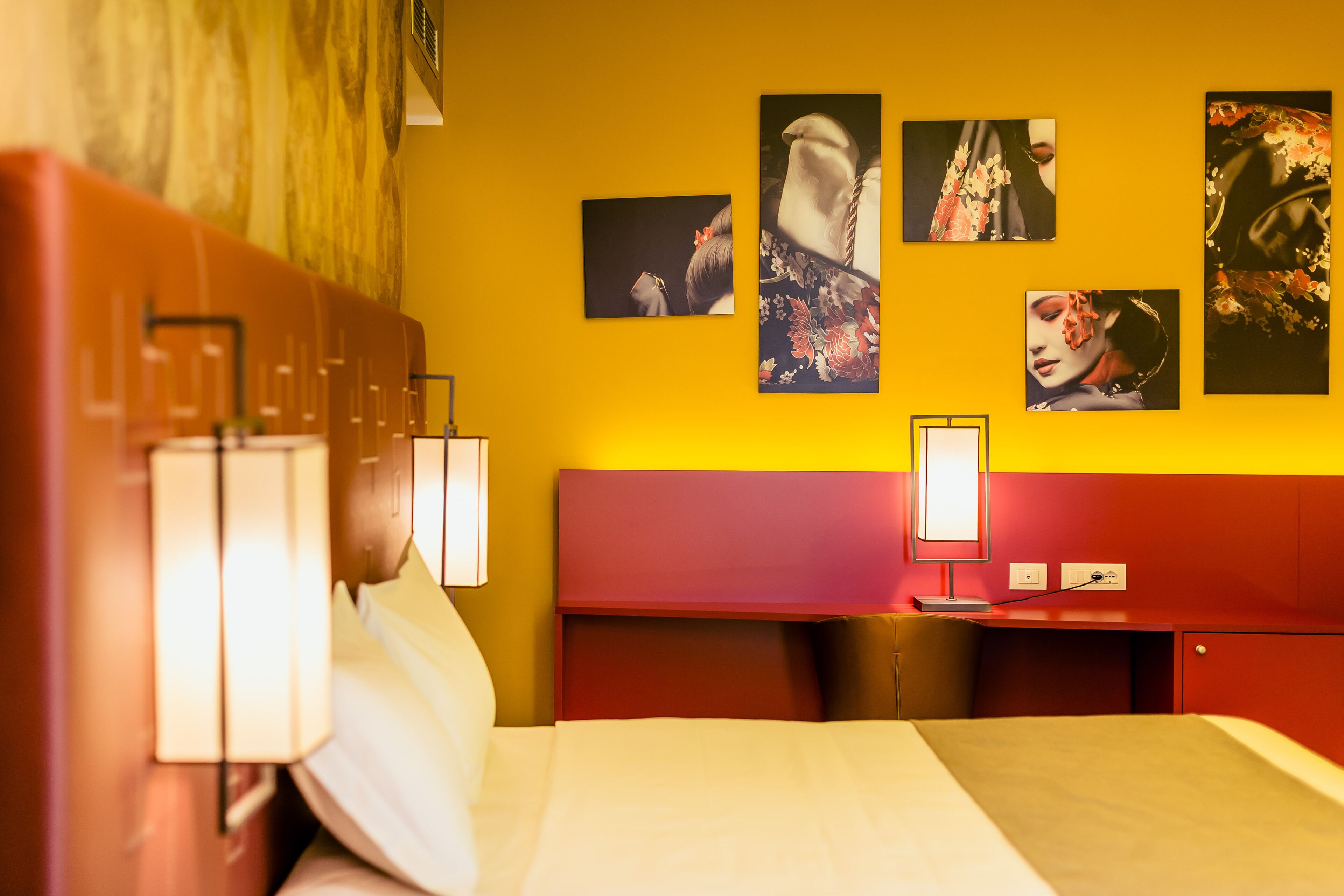 Una camera d'albergo con un letto, lampade sui comodini, una scrivania e un'opera d'arte incorniciata appesa al muro.