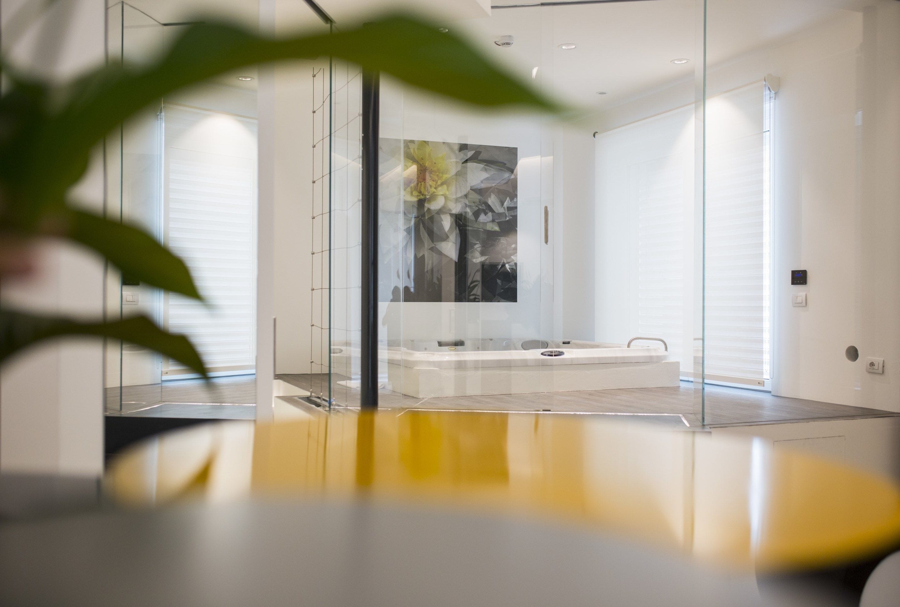Ein modernes Badezimmer mit Glasabtrennung, einem großen Spiegel und einem an der Wand befestigten Kunstwerk.