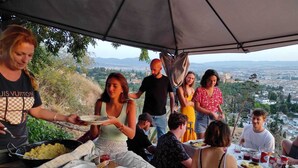 A group of people dining outdoors with a scenic city view in the background. - El Granado Hostel (Granada)