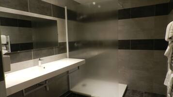 A modern bathroom with a white sink, a mirror, and a shower enclosure.