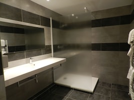 Un baño moderno con un lavamanos blanco, un espejo y una cabina de ducha.