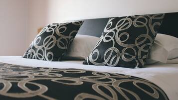 Una cama con almohadas y colcha de diseño blanco y negro.